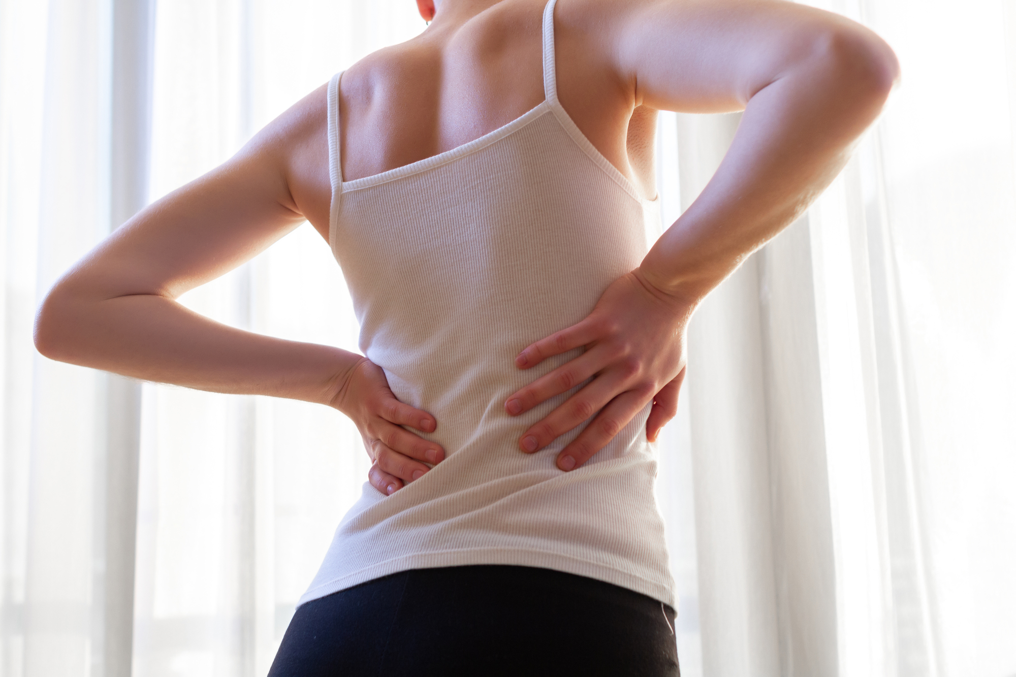 Young woman suffering from neck pain and backache, stretching Young woman suffering from neck pain and backache, stretching